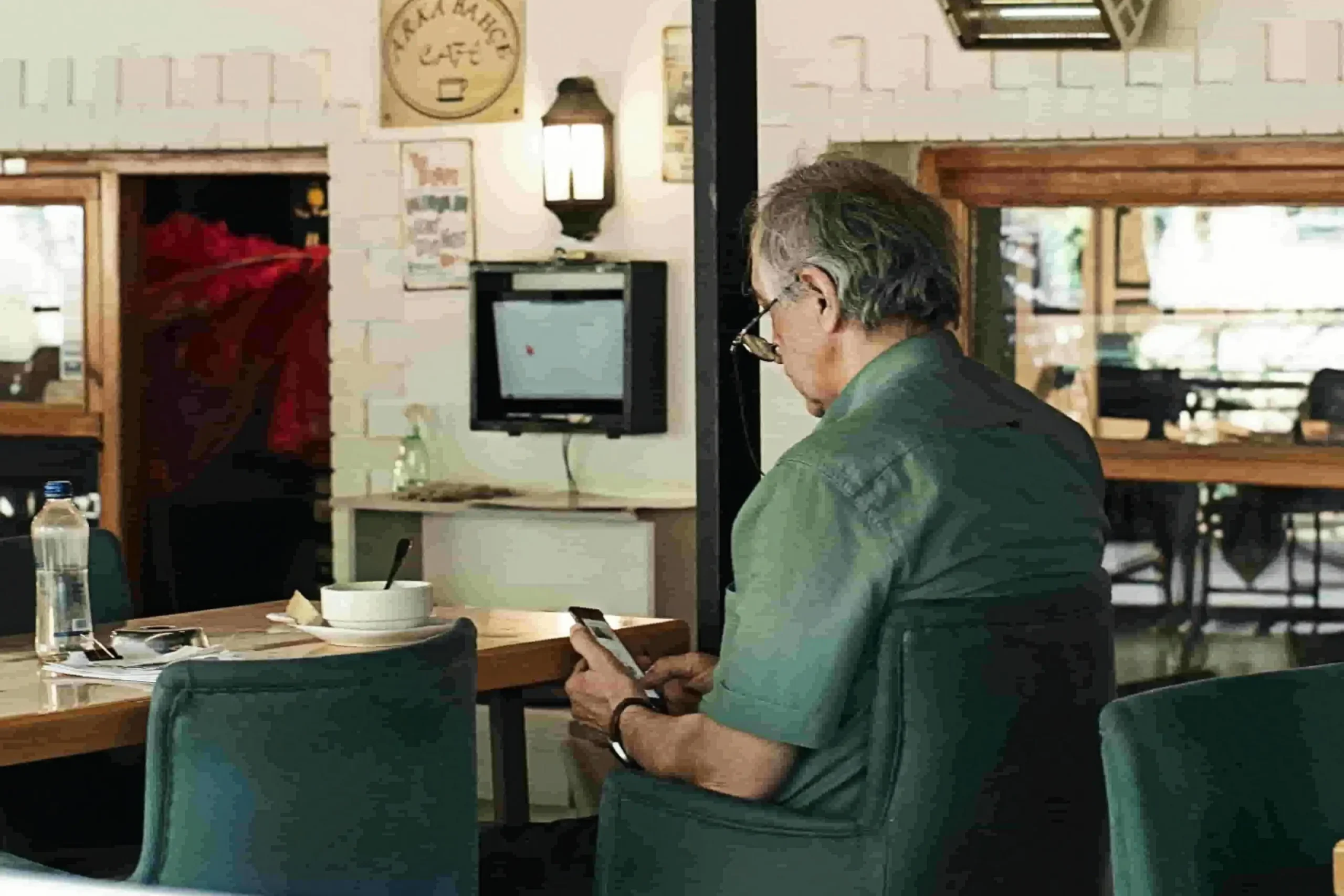 Mature man using smartphone in cafe representing OurTime dating app review
